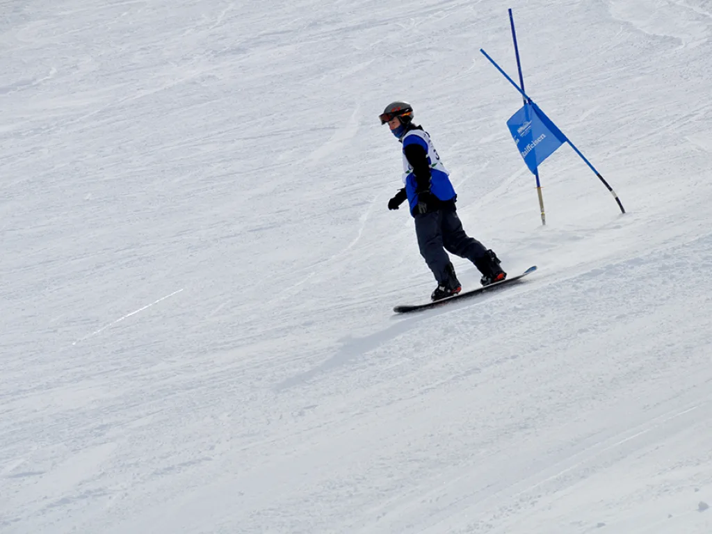 Snowboarder gleitet auf die Torstange zu.